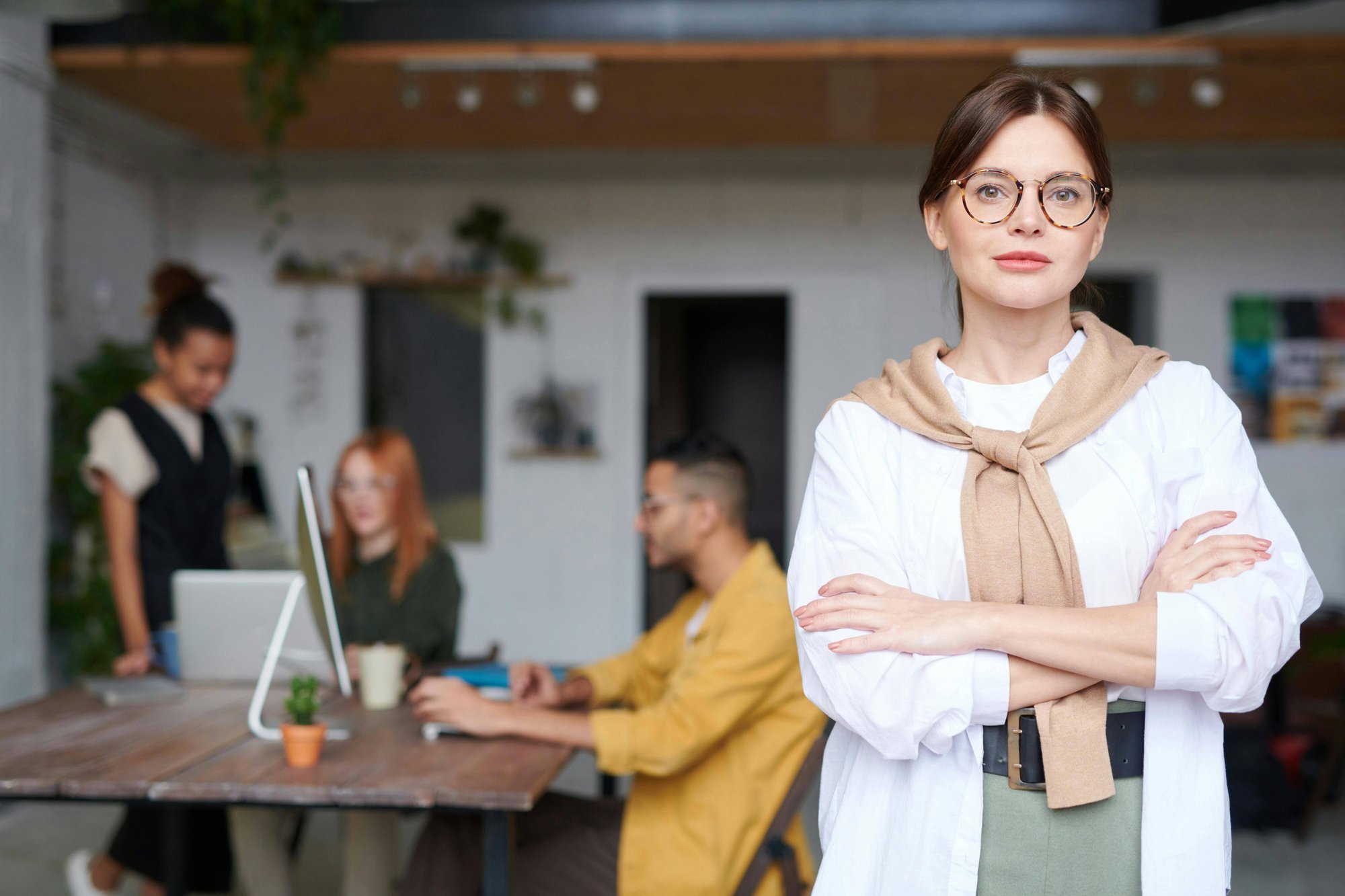 Woman standing in front of a group of other workers around a computer